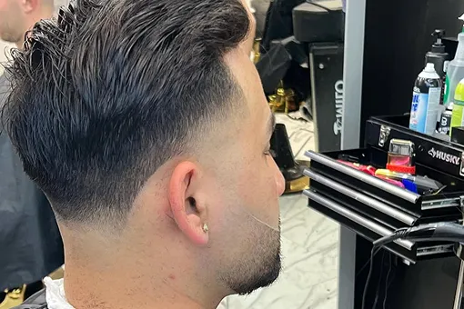 Dessus texturé coiffé vers l’arrière avec taper fade bas, au Salon de barbier Bill-K